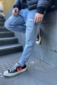 person in blue denim jeans and black and white converse all star high top sneakers